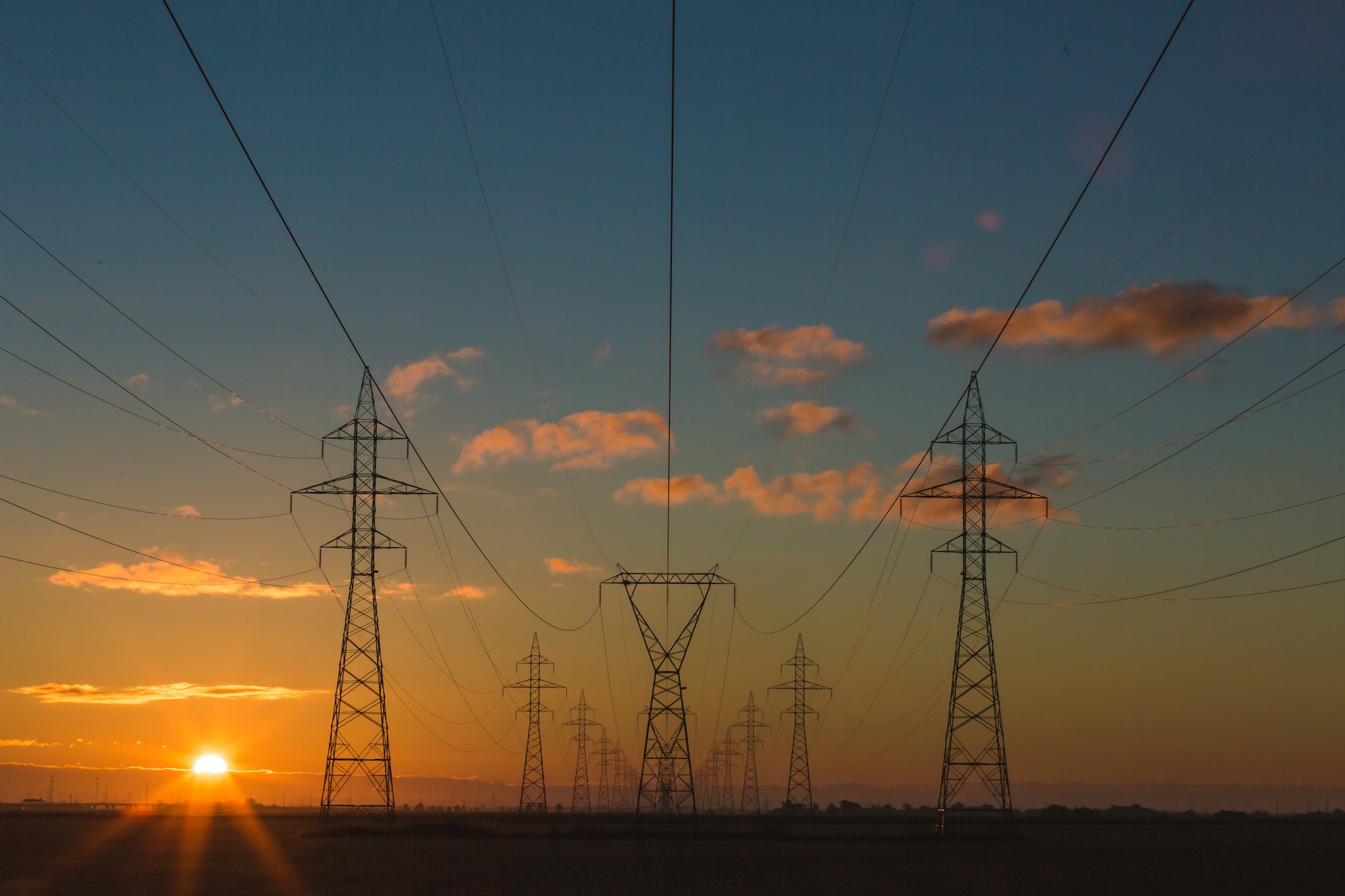 Power transmission infrastructure silhouetted against a golden sunset